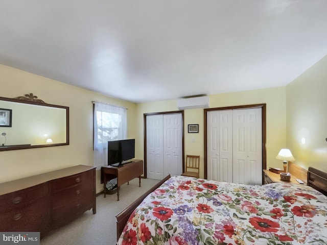 carpeted bedroom featuring a wall mounted AC and two closets