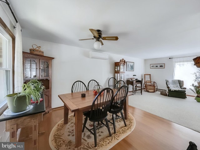 dining area with light hardwood / wood-style floors, a wall mounted AC, and ceiling fan