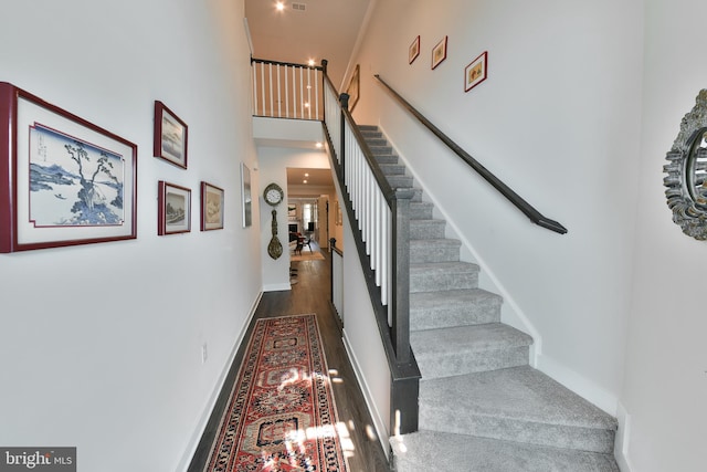 staircase featuring hardwood / wood-style floors and a towering ceiling