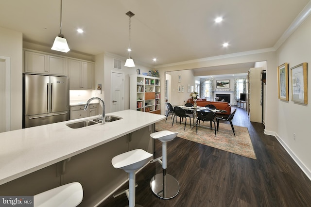 kitchen with sink, a kitchen bar, decorative light fixtures, and stainless steel refrigerator