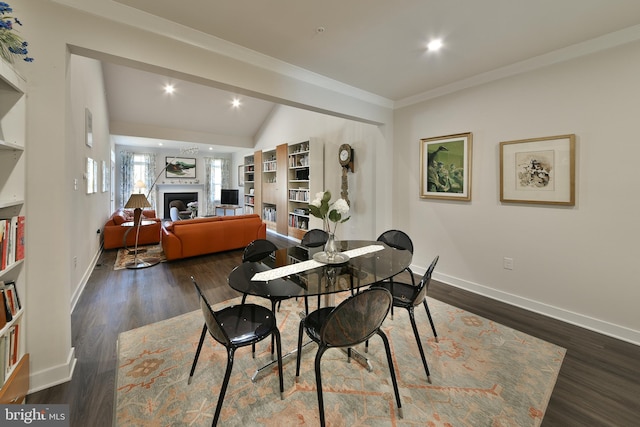 dining area featuring lofted ceiling, ornamental molding, and dark wood-type flooring