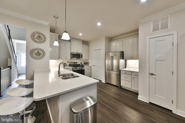 kitchen with dark wood-type flooring, kitchen peninsula, stainless steel appliances, sink, and decorative light fixtures