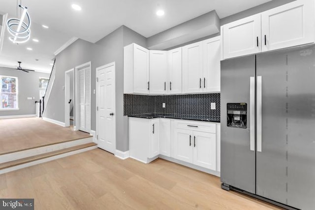 kitchen with decorative backsplash, stainless steel fridge, pendant lighting, white cabinetry, and light hardwood / wood-style flooring