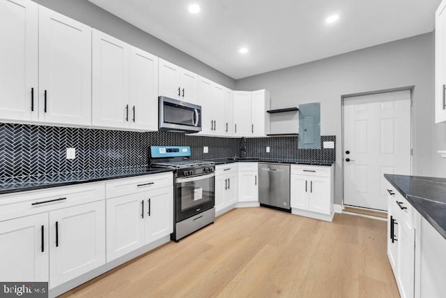 kitchen featuring white cabinets, stainless steel appliances, backsplash, and light hardwood / wood-style floors