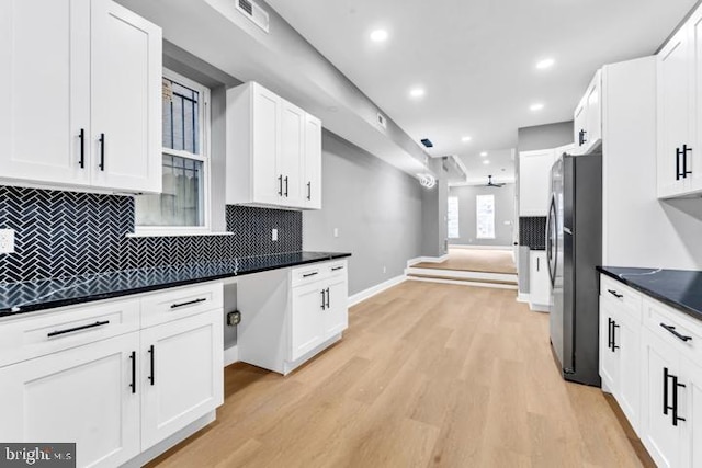 kitchen featuring stainless steel fridge, white cabinetry, light hardwood / wood-style floors, and backsplash