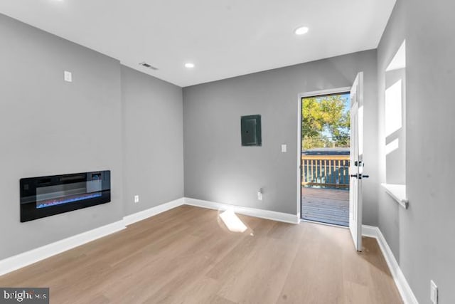 unfurnished living room with light wood-type flooring and electric panel