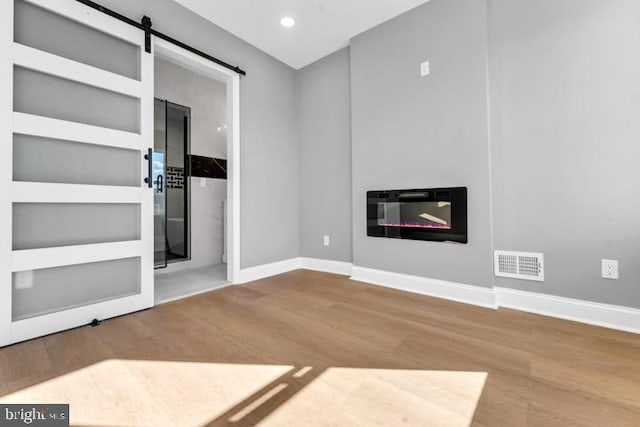 unfurnished living room featuring wood-type flooring and a barn door