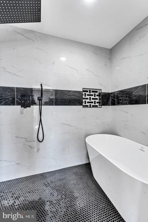 bathroom featuring a tub to relax in and tile walls