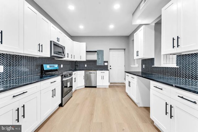 kitchen with white cabinets, stainless steel appliances, tasteful backsplash, and light hardwood / wood-style flooring