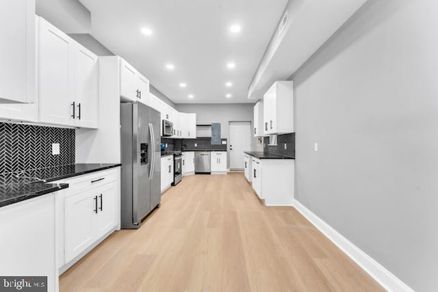 kitchen with appliances with stainless steel finishes, decorative backsplash, light hardwood / wood-style flooring, and white cabinets