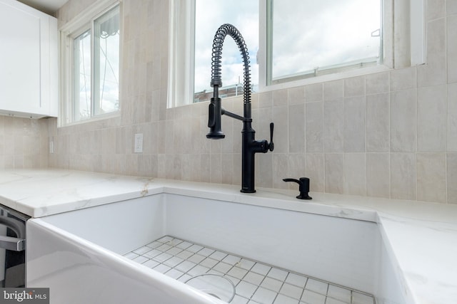 room details featuring light stone countertops, white cabinetry, sink, and tasteful backsplash