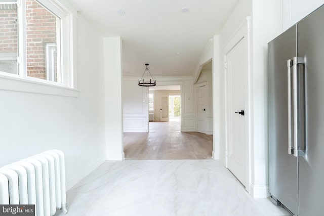 corridor featuring crown molding, radiator heating unit, and light hardwood / wood-style flooring