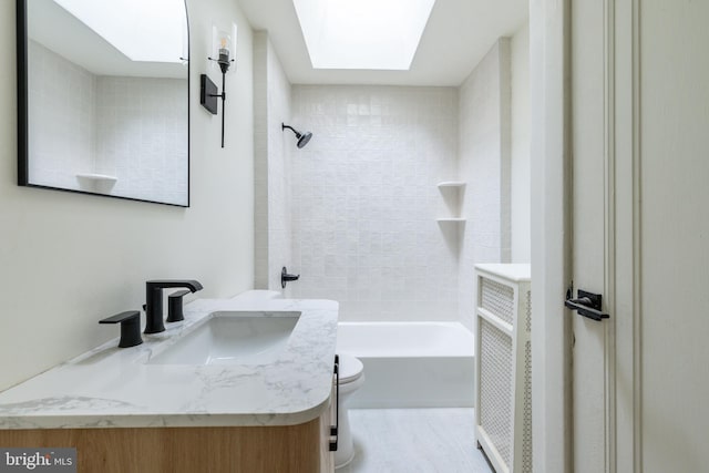 full bathroom with vanity, a skylight, toilet, and tiled shower / bath combo