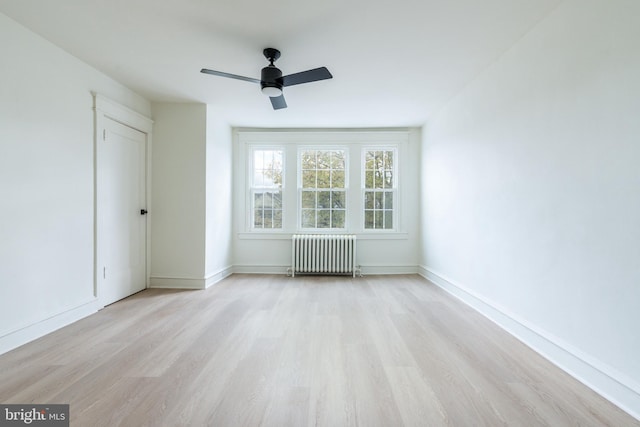 spare room with radiator heating unit, light hardwood / wood-style floors, and ceiling fan