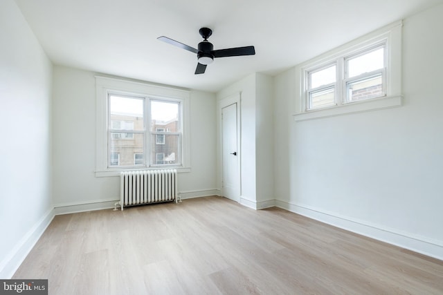 spare room featuring ceiling fan, radiator, and light hardwood / wood-style flooring