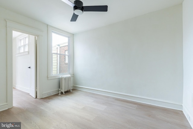 spare room with radiator heating unit, light wood-type flooring, and ceiling fan