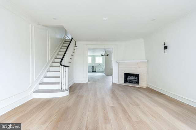 unfurnished living room with light hardwood / wood-style floors, ornamental molding, and sink