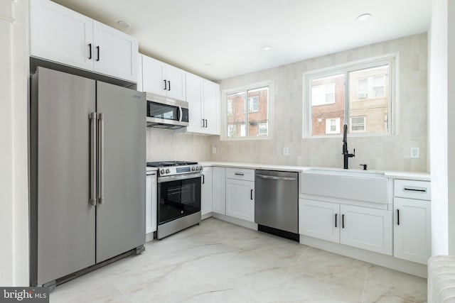 kitchen with white cabinets, decorative backsplash, stainless steel appliances, and sink