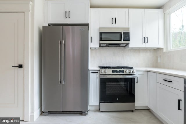 kitchen with white cabinets, decorative backsplash, and stainless steel appliances