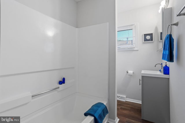 bathroom with hardwood / wood-style floors, a washtub, and vanity