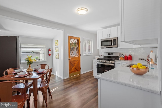 kitchen featuring sink, white cabinetry, stainless steel appliances, dark hardwood / wood-style floors, and light stone countertops