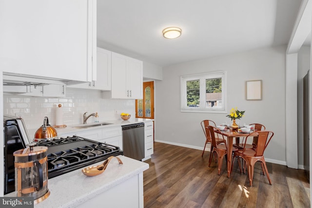 kitchen with stainless steel dishwasher, dark hardwood / wood-style floors, white cabinets, sink, and backsplash