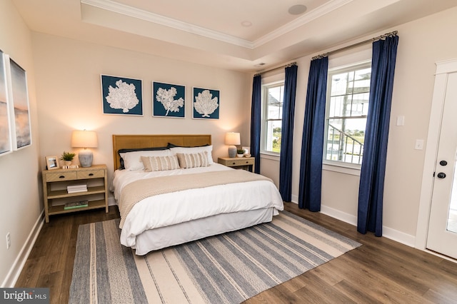 bedroom with baseboards, a tray ceiling, wood finished floors, and ornamental molding