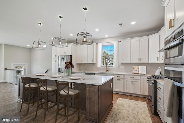 kitchen with tasteful backsplash, light countertops, appliances with stainless steel finishes, white cabinetry, and a sink