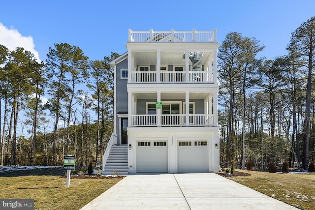 coastal home featuring stairs, concrete driveway, a balcony, and a garage