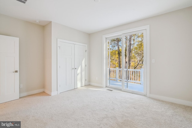 unfurnished bedroom with access to exterior, carpet, visible vents, and baseboards