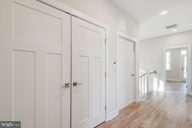 corridor featuring visible vents, baseboards, light wood-style flooring, an upstairs landing, and recessed lighting