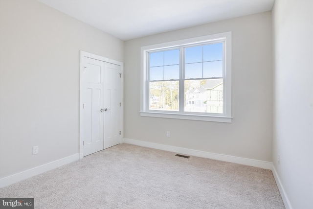 unfurnished bedroom with carpet, a closet, visible vents, and baseboards