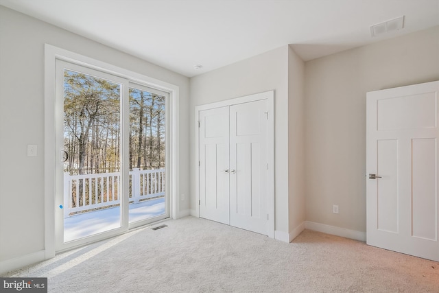 unfurnished bedroom with carpet floors, access to exterior, and visible vents