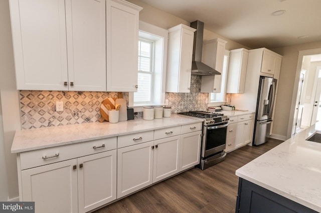 kitchen featuring tasteful backsplash, white cabinets, appliances with stainless steel finishes, dark wood-style flooring, and wall chimney range hood