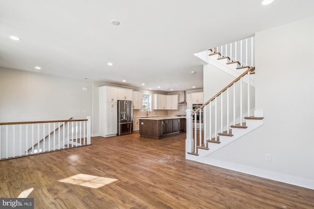 interior space with recessed lighting, a sink, wood finished floors, baseboards, and stairway