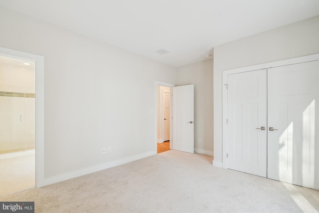 unfurnished bedroom with ensuite bathroom, a closet, carpet flooring, and baseboards