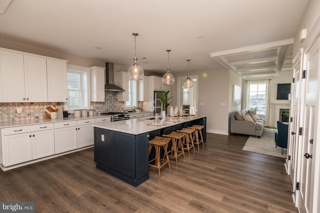 kitchen featuring wall chimney exhaust hood, white cabinetry, dark wood-type flooring, and stainless steel range with gas stovetop