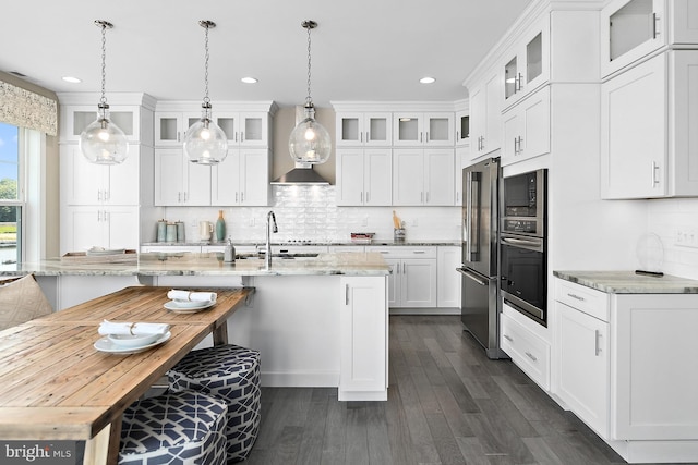 kitchen with light stone counters, white cabinetry, sink, and decorative light fixtures