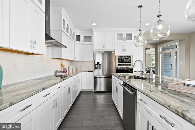 kitchen featuring hanging light fixtures, wall chimney range hood, appliances with stainless steel finishes, and white cabinetry