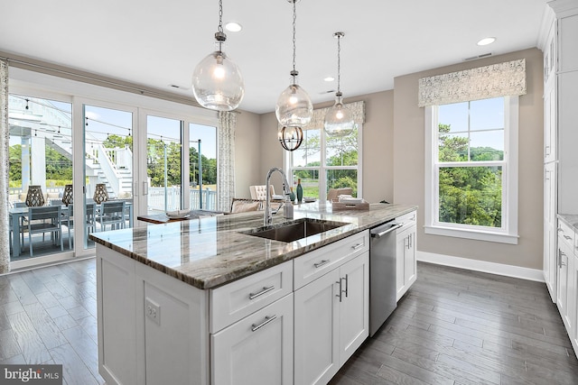 kitchen featuring light stone counters, white cabinets, a center island with sink, and sink