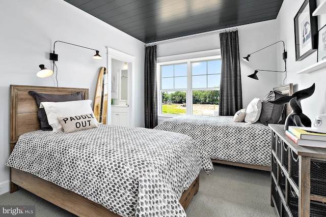 bedroom with ensuite bath, wood ceiling, and carpet flooring