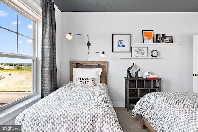 bedroom with carpet floors, wooden ceiling, and multiple windows