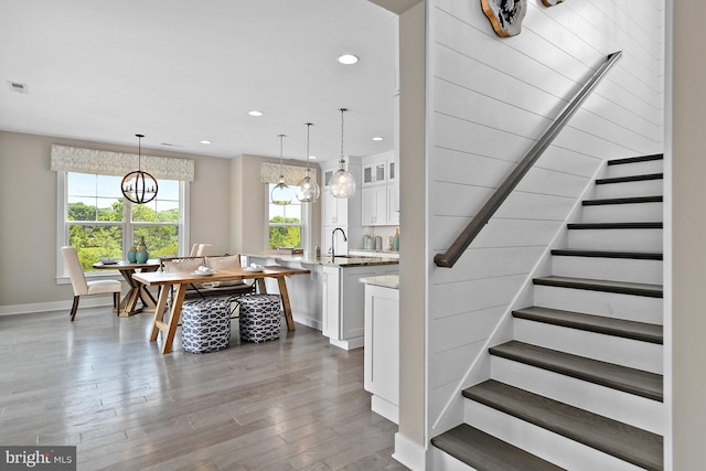 staircase with sink, a notable chandelier, and hardwood / wood-style flooring