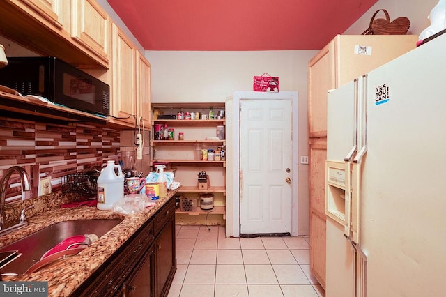 kitchen featuring light tile patterned floors, sink, white refrigerator with ice dispenser, light stone countertops, and decorative backsplash