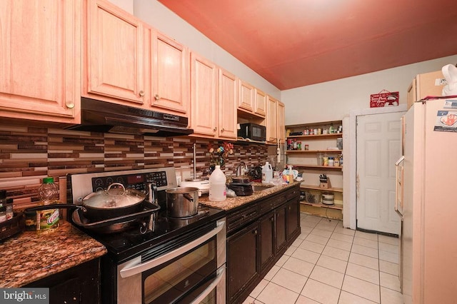 kitchen with white refrigerator, light tile patterned flooring, tasteful backsplash, dark stone counters, and stainless steel range with electric cooktop