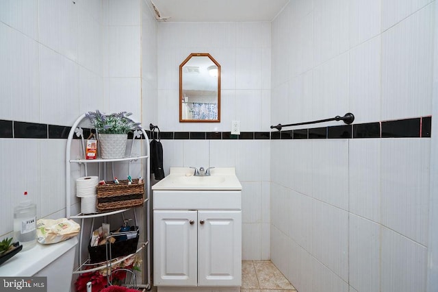 bathroom featuring tile patterned floors, vanity, toilet, and tile walls