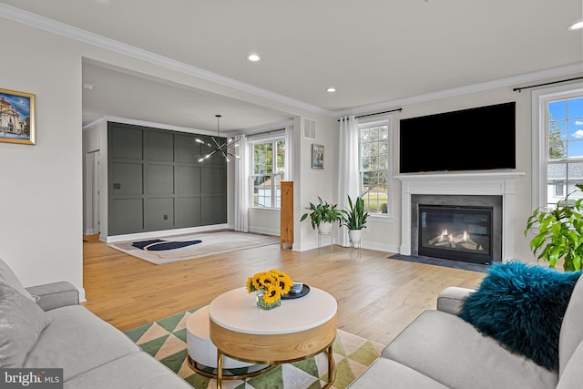 living room with a wealth of natural light, ornamental molding, and light hardwood / wood-style flooring