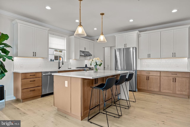 kitchen featuring white cabinetry, stainless steel appliances, light wood-type flooring, and a kitchen island