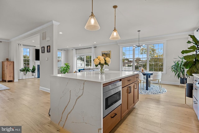 kitchen featuring ornamental molding, a center island, light wood-type flooring, and a wealth of natural light