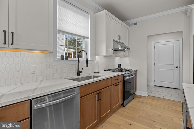 kitchen featuring white cabinets, appliances with stainless steel finishes, light stone countertops, light hardwood / wood-style flooring, and sink